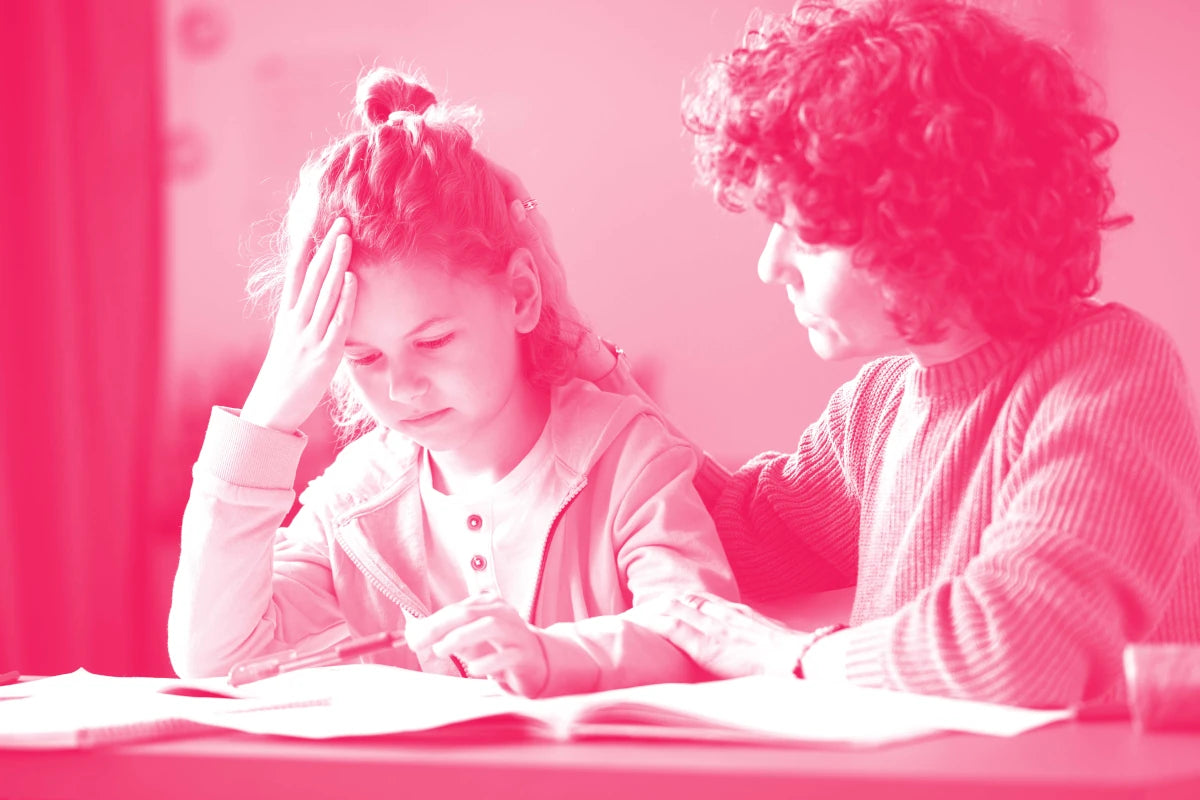 bambina che studia su un banco di scuola aiutata da docente